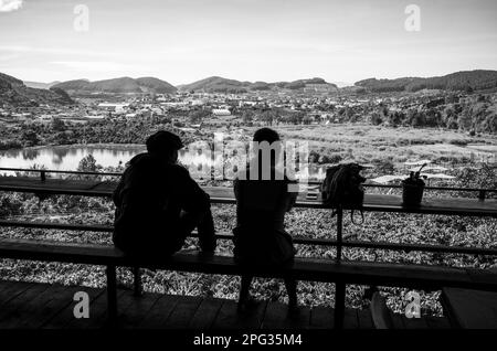 Una giovane coppia vietnamita si siede al Me Linh Coffee Garden e guarda fuori attraverso alberi di caffè, Dap Cam Ly Lake e una valle nelle Highlands centrali nea Foto Stock