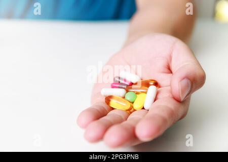 Primo piano di pillole colorate, capsule medicamenti nelle mani dell'uomo. Concetto di assistenza medica e sanitaria o malattia. Foto Stock