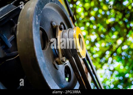 Puleggia condotta di un trattore retrostante con due cinghie in primo piano su uno sfondo sfocato. Motore per trattore piccolo per dissodamento da giardino Foto Stock