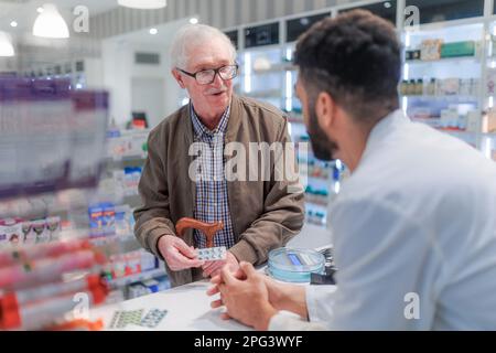 Giovane farmacista che spiega al cliente come dosare il farmaco. Foto Stock