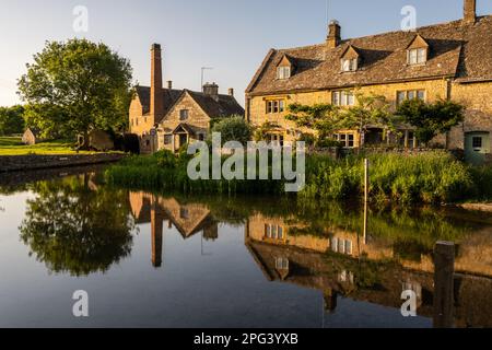 Il tradizionale mulino ad acqua e cottage in pietra si riflettono nel River Eye nel villaggio di macellazione inferiore in Inghilterra Cotswolds. Foto Stock