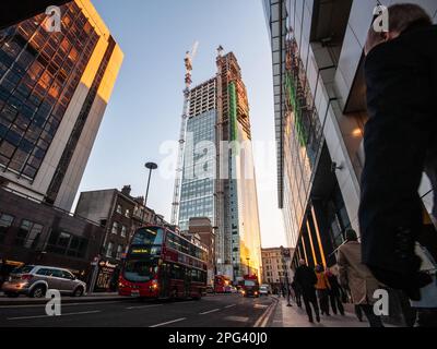 I pedoni e il traffico passano davanti al grattacielo degli uffici della Heron Tower in costruzione nel quartiere finanziario della City of London. Foto Stock