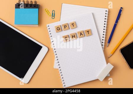 Lavora e studia il background con l'aiuto di un bot chatGPT. Parole in lettere di legno. Vista da tavolo con spazio di copia del notebook aperto. Chat GPT per lavorare e creare. Ucraina, Kiev - 21 febbraio 2023 Foto Stock