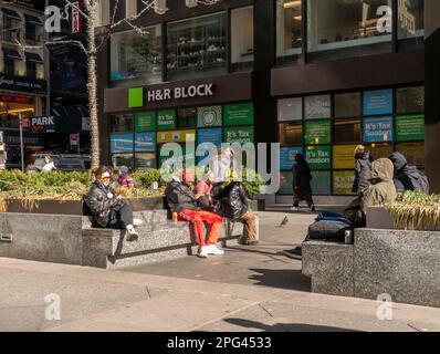 La gente gode il sole in una piazza di fronte a un ufficio H&R Block nel quartiere dell'abbigliamento di New York mercoledì 8 marzo 2023. (© Richard B. Levine) Foto Stock