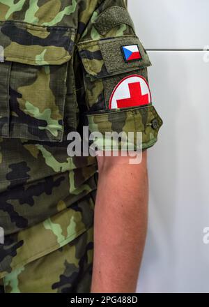 Brno, Czechia - 08 ottobre 2021: Croce rossa e bandiera ceca sulla moderna manica uniforme di soldato medico, dettaglio primo piano Foto Stock