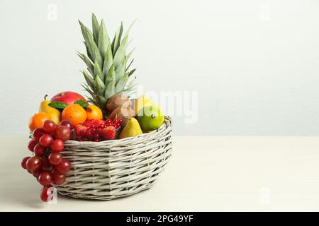 Cestino di vimini con frutta fresca diversa su un tavolo di legno bianco. Spazio per il testo Foto Stock