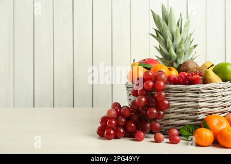 Cestino di vimini con frutta fresca diversa su un tavolo di legno bianco. Spazio per il testo Foto Stock