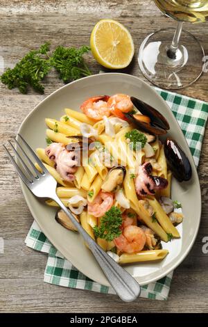 Deliziosa pasta con frutti di mare servita su tavolo in legno, piatto Foto Stock