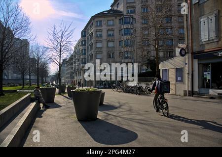 Sconosciuto addetto alla consegna delle biciclette che attraversa un piccolo parco a Ginevra, in Svizzera durante l'inverno Foto Stock