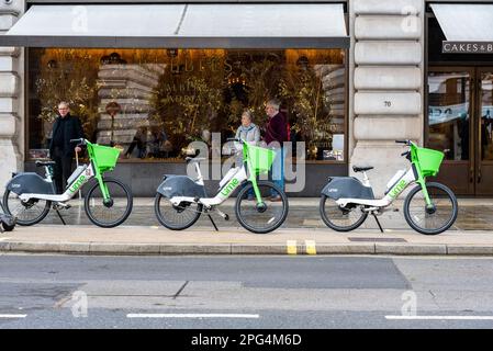 Noleggio bici elettrica al lime biciclette lasciate fuori dal negozio di dolci e bolle in Regent Street. Noleggio biciclette Dockless lasciato sul marciapiede nella zona turistica Foto Stock