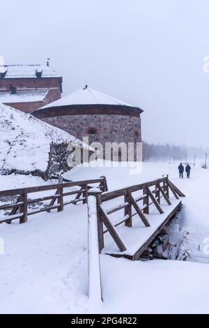 Cannone torre del castello di Hame (Tavastia castello) con ponte in legno in primo piano. Giornata innevata in inverno. Hameenlinna, Finlandia. Foto Stock