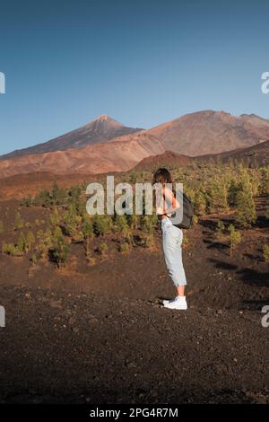 Chica con mochilla contemplando el pico Teide mientra hace una ruta de senderismo en Tenerife. Foto Stock