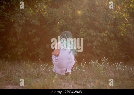 Bambina con capelli verdi raccoglie fiori selvatici in mazzo da regalare alla madre nel prato. A piedi in viaggio nei fine settimana con la famiglia in countrysid Foto Stock