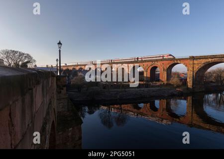 LNER Bi mode Azuma treno che corre su Diesel attraversando il viadotto Yarm arco in mattoni, contea Durham, riflesso nel fiume Tees Foto Stock