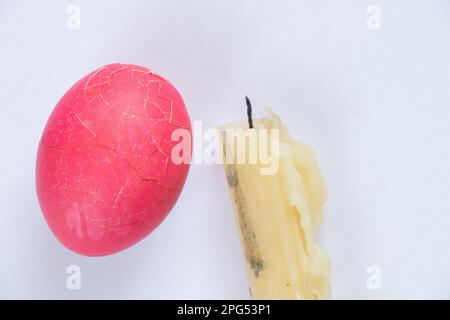 Uovo di Pasqua rotto e candela estinta su un bianco Foto Stock