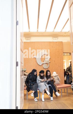 Londra, Regno Unito -15 dicembre 2022, tre ragazze sono sedute su una panchina in una gioielleria boutique guardando i loro telefoni cellulari. Foto Stock