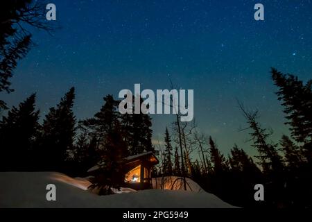 Stelle sopra una cabina remota nella neve in una foresta in Norvegia Foto Stock