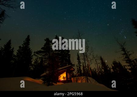 Stelle sopra una cabina remota nella neve in una foresta in Norvegia Foto Stock