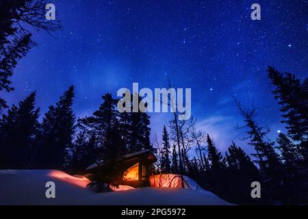 Stelle sopra una cabina remota nella neve in una foresta in Norvegia Foto Stock