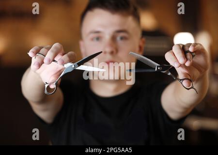 Barbiere. Irriconoscibile parrucchiere sta tenendo due tipi di forbici. Barbiere attrezzi professionali. Taglio di capelli maschio, moda. Parrucchiere, taglio di capelli e shav Foto Stock