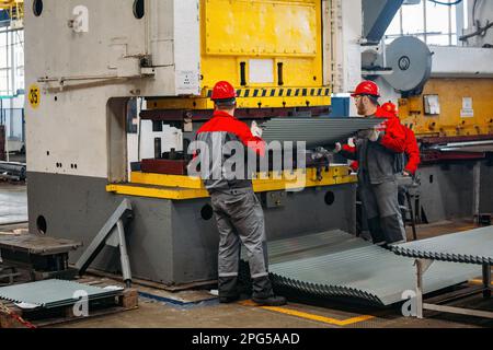 Operatori tecnici che lavorano con lamiera su pressa idraulica CNC. Foto Stock