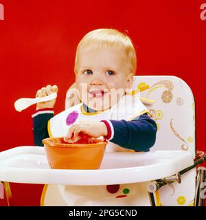 1970S BAMBINO BIONDO SORRIDENTE GUARDANDO LA MACCHINA FOTOGRAFICA SEDUTA IN SEGGIOLONE MANO DESTRA TENENDO IL CUCCHIAIO SINISTRA ATTACCANDO LA MANO DENTRO FOOD BOWL - KB10042 HAR001 HARS VISO RISATA BIONDA BAMBINO FELICE GIOIA LIFESTYLE SODDISFAZIONE STUDIO SHOT SALUBRITÀ HOME VITA COPIA SPAZIO MASCHI ESPRESSIONI FELICITÀ TESTA E SPALLE ALLEGRO CHE SI ATTACCA IN DESTRA SORRISI GIOIOSO BAMBINO RAGAZZO AFFASCINANTE CRESCITA SEGGIOLONE I GIOVANI HANNO LASCIATO L'ETNIA CAUCASICA HAR001 VECCHIO STILE Foto Stock