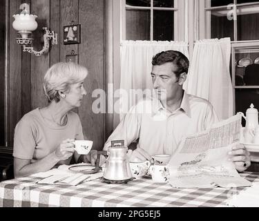 1970S COPPIA MATURA CHE PARLA BERE CAFFÈ IN CUCINA TAVOLO DA PRANZO UOMO IN POSSESSO DI LEGGERE GIORNALE - S20518 HAR001 HARS VECCHIA MODA CONVERSAZIONE PENSIONATO 1 COMUNICAZIONE INFORMAZIONI LAVORO DI SQUADRA LIFESTYLE FEMMINE SPOSATO CONIUGE MARITI HOME VITA COPIA SPAZIO AMICIZIA METÀ LUNGHEZZA SIGNORE PERSONE MASCHI PENSIONAMENTO MEDIO-VECCHIO B&W PARTNER MEDIO-VECCHIO UOMO ANZIANO PENSIONATO MEDIO-VECCHIO DONNA BEVANDA TEMPO LIBERO FLUIDO COLLEGAMENTO SUPPORTO CAFFEINA JOE COOPERAZIONE JAVA TOGETHERNESS MOGLI BEVANDE BIANCO E NERO ETNICITÀ CAUCASICA HAR001 VECCHIO STILE Foto Stock