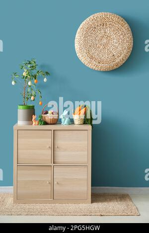 Decorazioni pasquali su armadio in legno vicino alle pareti blu Foto Stock