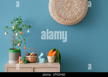 Decorazioni pasquali su armadio in legno vicino alle pareti blu Foto Stock