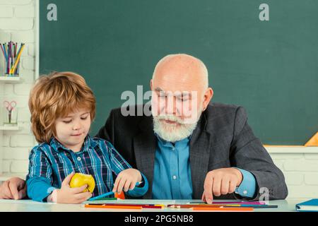 Concetto di apprendimento e di istruzione. Uomo con vecchio insegnante che impara in classe su sfondo a colori. Carino bambino prescolare uomo ragazzo con nonno in un Foto Stock