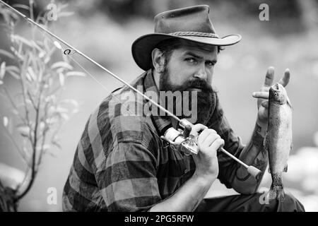 Ritratto dell'uomo in vacanza. Pesca sfondo. Avventure di pesca del mosca. Uomo vestito di pesca camicia con canna sul lago. Tempo del fine settimana. Pescatore uomo Foto Stock