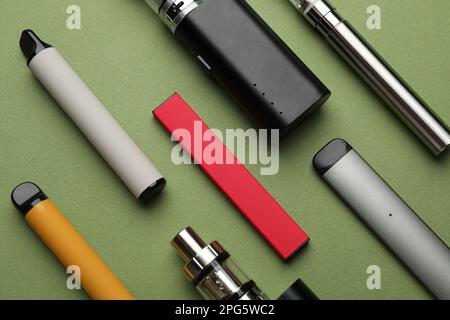 Molti apparecchi elettronici per fumare su fondo di oliva, piatto Foto Stock