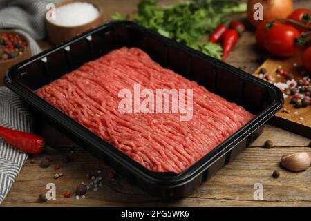 Carne macinata in contenitore di plastica e altri ingredienti su tavola di legno Foto Stock