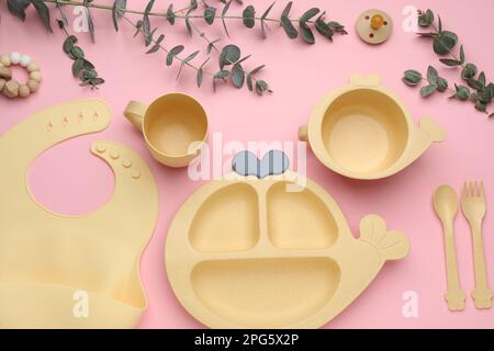 Set di stoviglie in plastica e accessori per bambini su sfondo rosa, piatto Foto Stock