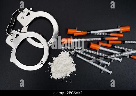 Concetto di crimine della droga con polvere bianca e siringa usa e getta su sfondo nero Foto Stock