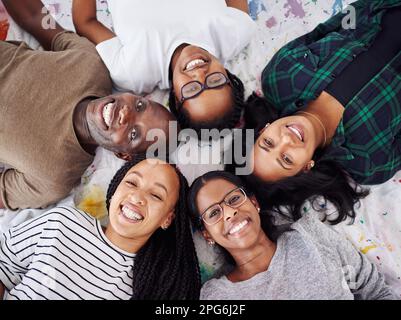 Circondatevi di persone con la stessa mentalità. Inquadratura ad angolo alto di un gruppo di persone che formano un cerchio sul pavimento. Foto Stock