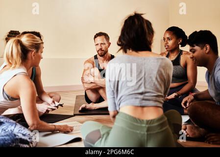 Lezione di yoga, dove il vostro cerchio interiore vi porta la pace interiore. un gruppo di giovani uomini e donne che chiacchierano durante una lezione di yoga. Foto Stock