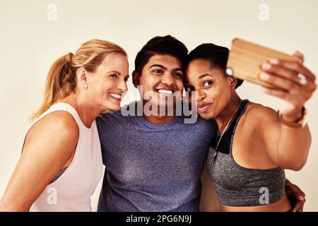 Che cosa è un workout senza gli amici impressionanti. un gruppo di giovani uomini e donne che prendono selfie in classe yoga. Foto Stock