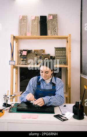 Riparatore svitando le viti dalla custodia del computer portatile con un cacciavite per la riparazione e la manutenzione. Riparazione e manutenzione di computer portatili Foto Stock