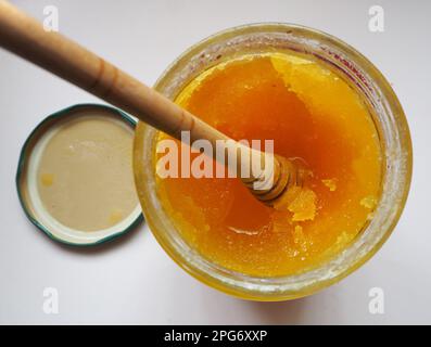 Miele cristallizzato sgocciolando da un cucchiaio di legno. Foto Stock