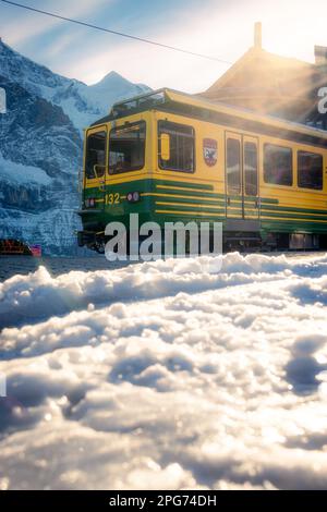 Un treno giallo in piedi ad una stazione in montagna Foto Stock