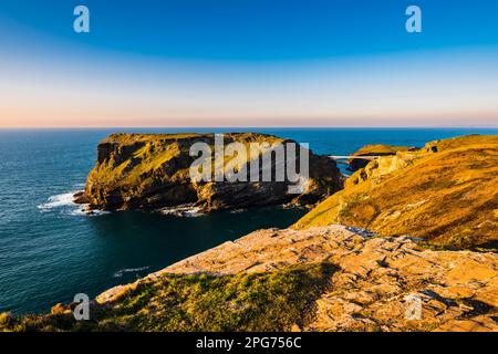 Il bagliore arancione della luce del sole sull'isola di Tintagel, preso da Glebe Cliff, Tintagel, Cornovaglia, Regno Unito Foto Stock