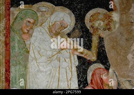 Santa Maria bacia la mano morta di suo figlio Gesù mentre il suo corpo si abbassa dalla croce, mentre un'altra donna, probabilmente Maria Maddalena, gli bacia i piedi. Inizio 1300s Scuola di Giotto deposizione o discesa dalla Croce affresco nel chiostro della Chiesa dei Francescani, la chiesa del convento francescano di Bolzano, Alto Adige, Trentino-Alto Adige, Italia. Foto Stock