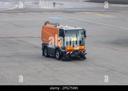 Un piccolo camion di pulizia con scope guida sulla pista Foto Stock