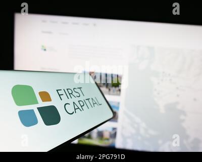 Smartphone con il logo della società immobiliare canadese First Capital REIT sullo schermo di fronte al sito Web. Messa a fuoco al centro a sinistra del display del telefono. Foto Stock
