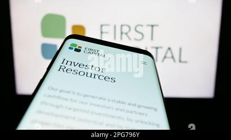Telefono cellulare con sito web della società immobiliare canadese First Capital REIT sullo schermo di fronte al logo. Messa a fuoco in alto a sinistra del display del telefono. Foto Stock