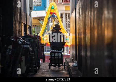 Traffico in un vicolo scuro, alla fine del quale è un altare con Dio indù Brahma, Bangkok, Thailandia Foto Stock