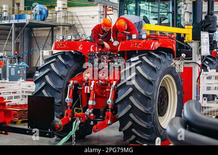 I lavoratori industriali assemblano il trattore agricolo in officina. Foto Stock