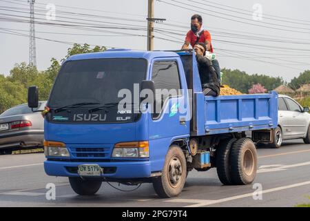 BANGKOK, THAILANDIA, MAR 11 2023, gli uomini siedono sul retro di un camion in movimento carico di sabbia e borse Foto Stock