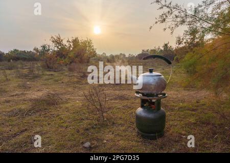 Un bollitore da campeggio viene bollito su una bottiglia di gas Foto Stock